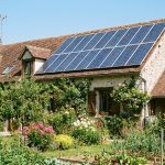 Toit de maison individuelle française avec panneaux solaires photovoltaïques, ciel dégagé, jardin