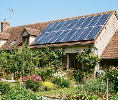Toit de maison individuelle française avec panneaux solaires photovoltaïques, ciel dégagé, jardin