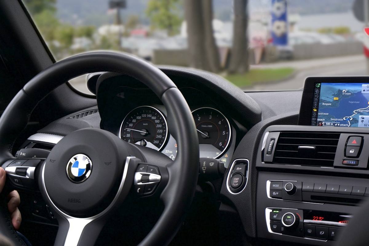 Intérieur d'une BMW, main sur le volant, navigation active sur l'écran