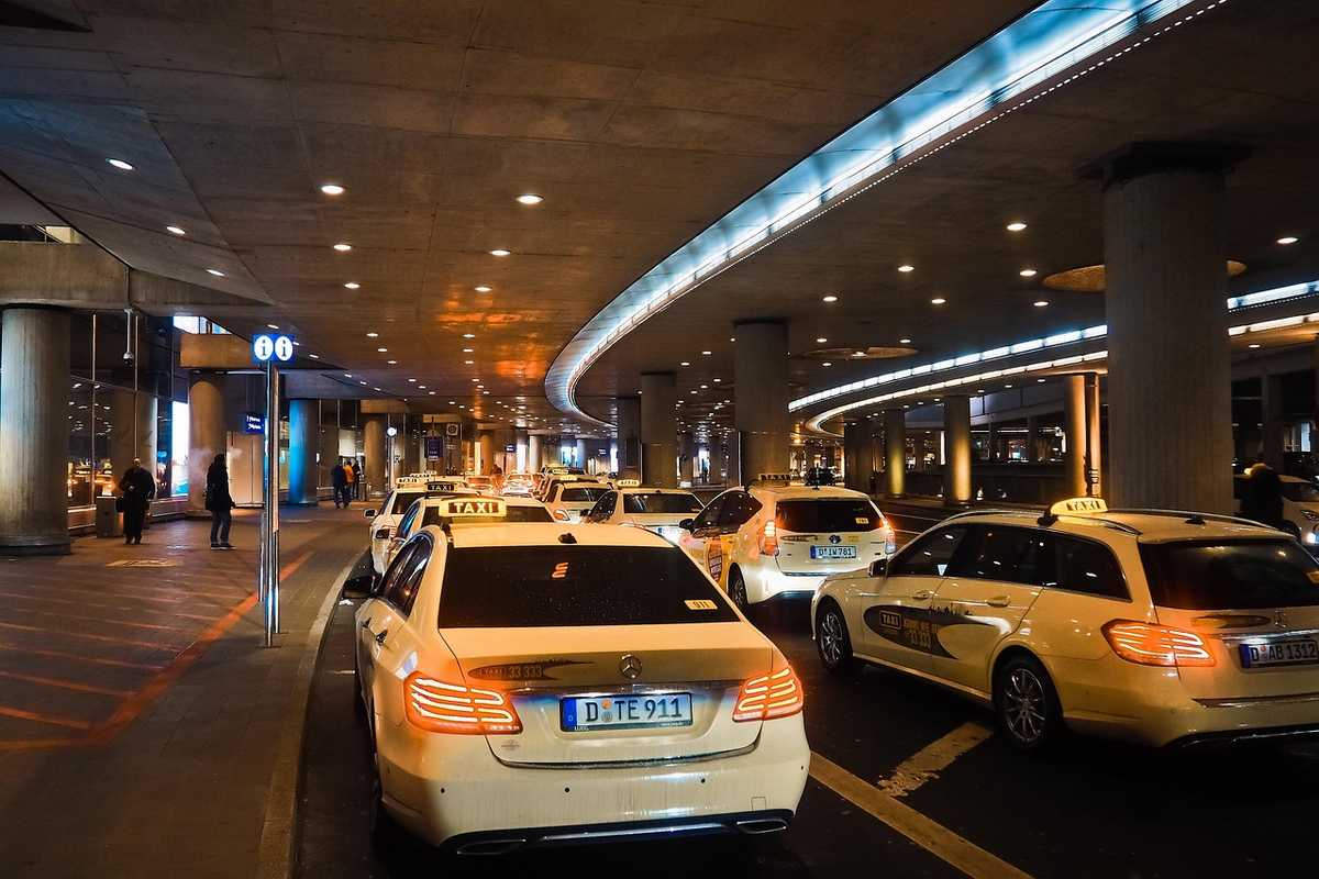 Des voitures-taxis attendent sous un hall souterrain éclairé