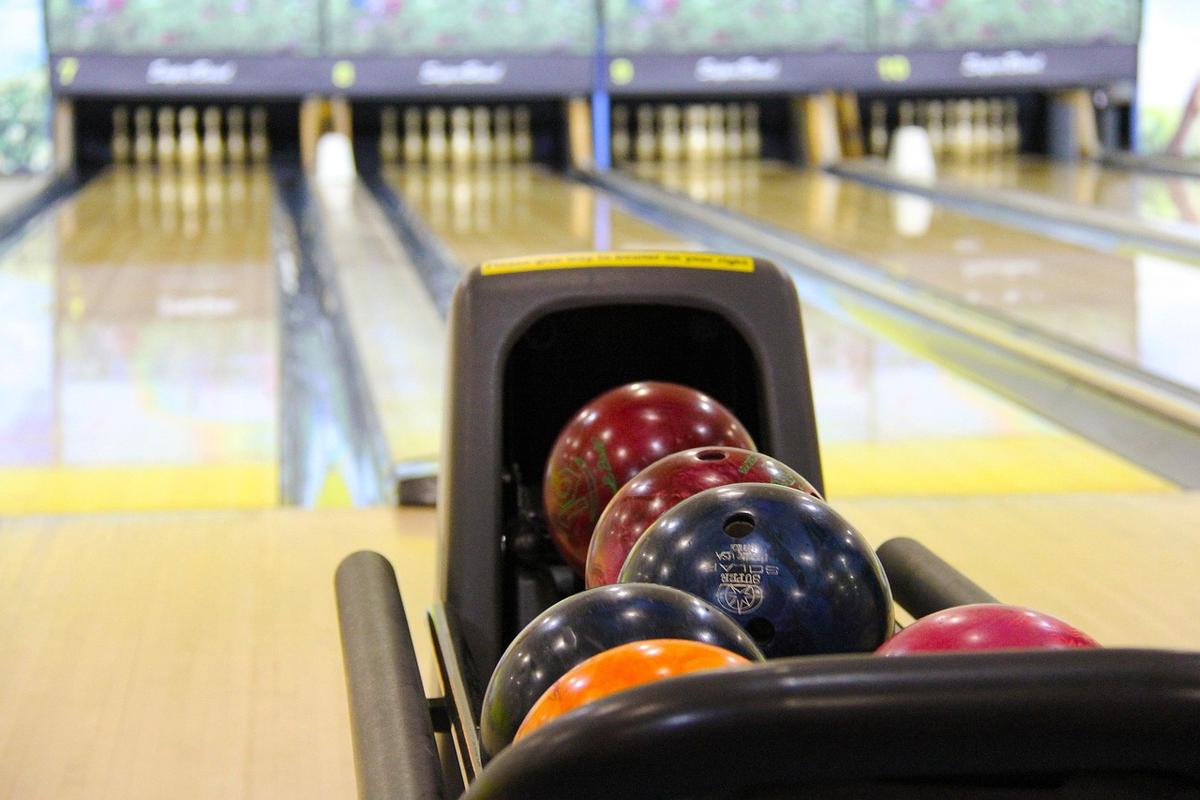 Boules de bowling dans un lanceur, allée et quilles visibles