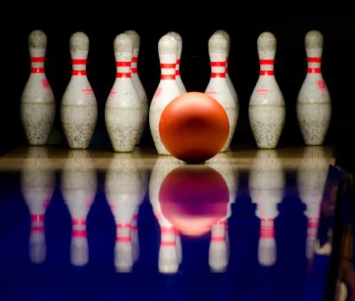 Boule rouge au centre, quilles blanches alignées sur lane
