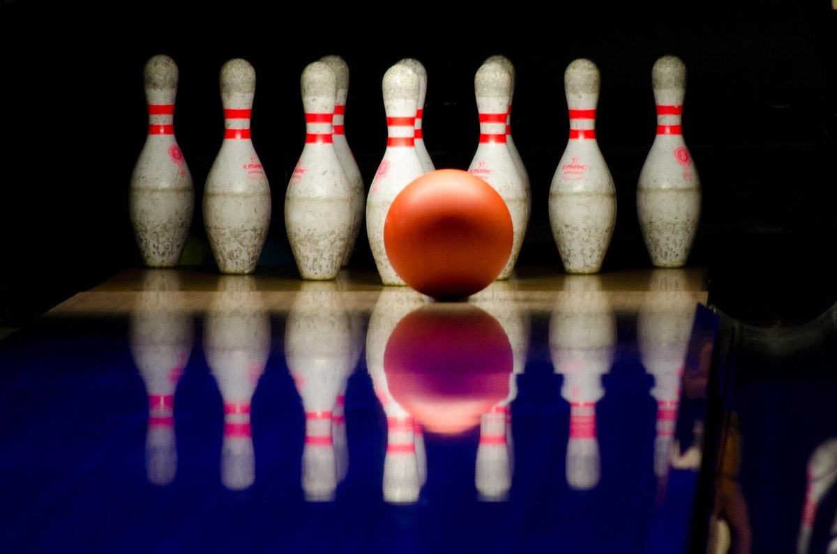 Boule rouge au centre, quilles blanches alignées sur lane