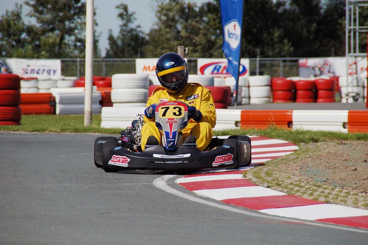 Un pilote en combinaison jaune pilote un kart de course sur virage