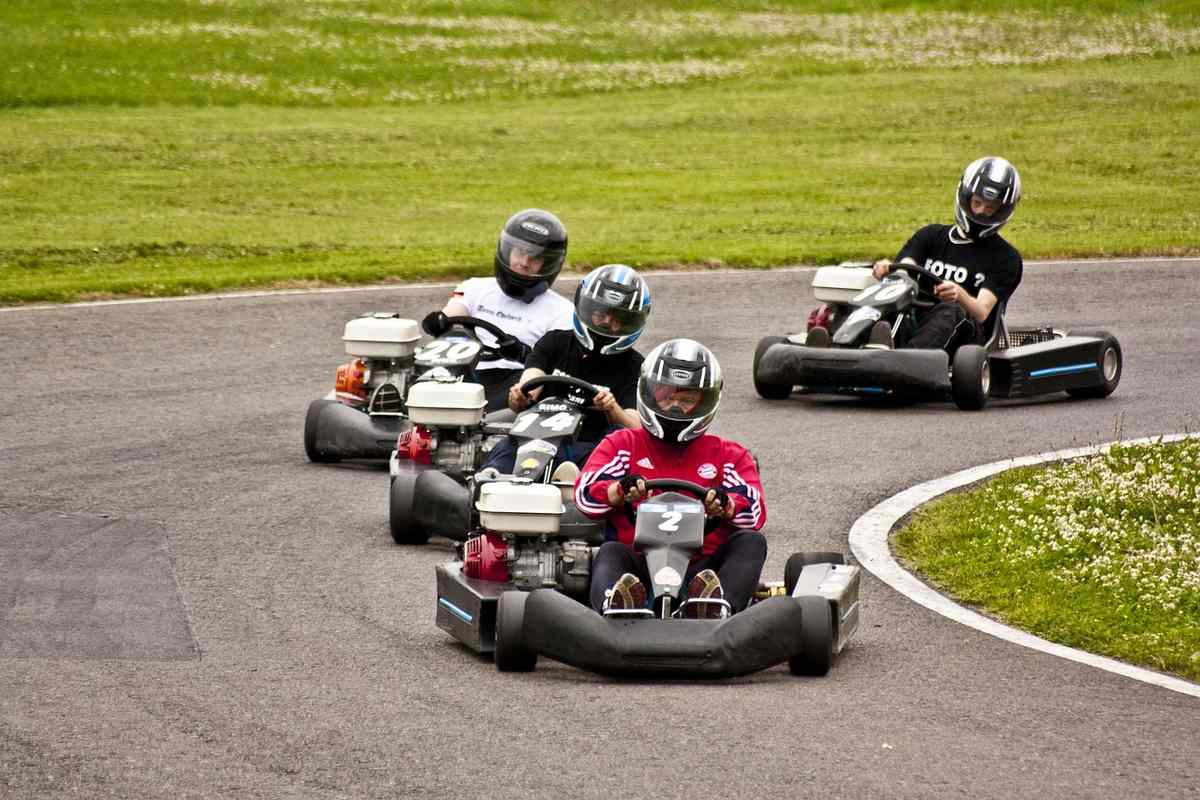 Quatre conducteurs en karting, casques, sur un virage de circuit Quatre conducteurs en karting, casques, sur un virage de circuit