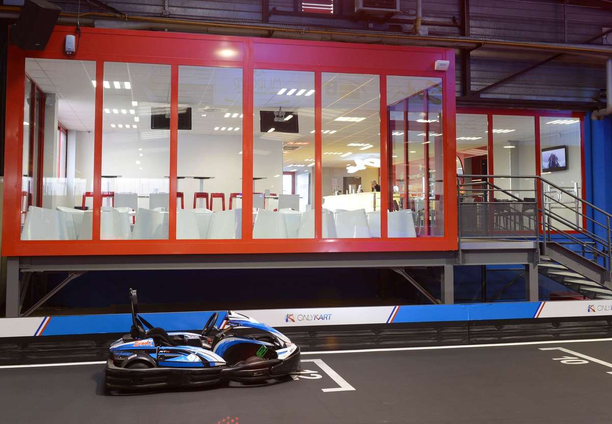 Un kart sur piste intérieure devant une salle vitrée