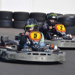 Deux enfants en karting sur une piste avec des pneus en arrière-plan