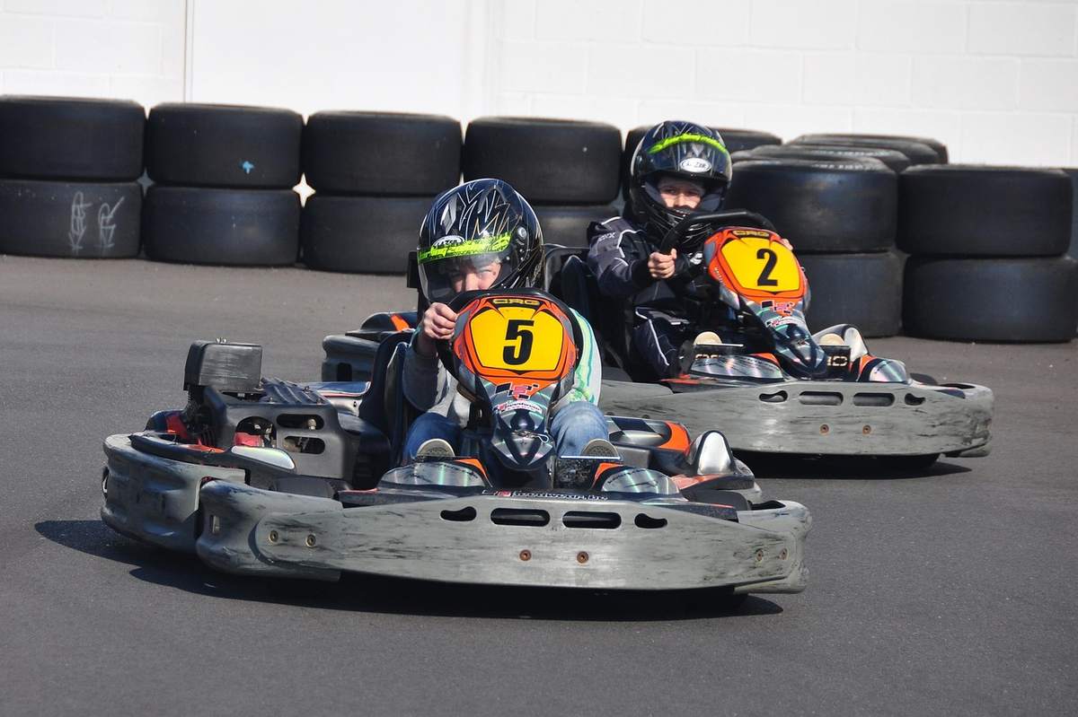 Deux enfants en karting sur une piste avec des pneus en arrière-plan