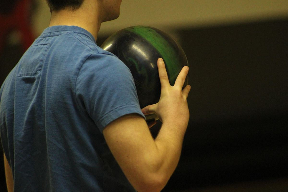 Un homme tient une boule de bowling dans une salle de bowling Un homme tient une boule de bowling dans une salle de bowling