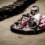 Un enfant conduit un kart rose sur un circuit de karting