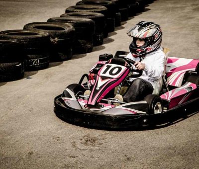 Un enfant conduit un kart rose sur un circuit de karting