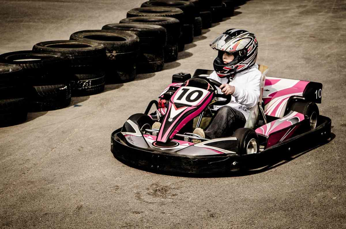Un enfant conduit un kart rose sur un circuit de karting